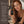 A woman with wet red hair holds a small amber dropper bottle labeled FRANCIS MICHAEL Cleansing Oil in a spa-like setting. The left side has a dark brown panel with the text 'Why it works,' and bullet points about ingredients, plus small certification logos near the bottom.