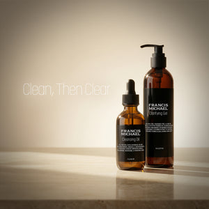 Two bottles of Francis Michael skincare products, Francis Michael Cleansing Oil and Francis Michael Clarifying Gel, on a beige background