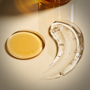 Two glass dishes with yellow liquid, Francis Michael Cleansing Oil, and a clear liquid, Francis Michael Clarifying Gel, on a light background