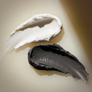 Two swatches, Francis Michael Exfoliating Paste and Francis Michael Detoxifying Mask, one white and one black, on a beige background.