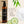 Francis Michael Clarify Cleansing Gel in an amber bottle with a black pump and black label, shown beside product benefits text, green leaves, cucumber slices, and a foam circle on a light beige background.