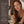 A woman with wet red hair holds a small amber bottle of Francis Michael Cleansing Oil. The left side features a dark brown panel with the word 'Clean' and a list of ingredients and benefits, including pomegranate oil, pumpkin seed oil, and witch hazel oil.