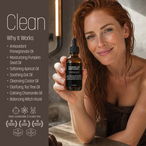 A woman with wet red hair holds a small amber bottle of Francis Michael Cleansing Oil. The left side features a dark brown panel with the word 'Clean' and a list of ingredients and benefits, including pomegranate oil, pumpkin seed oil, and witch hazel oil.