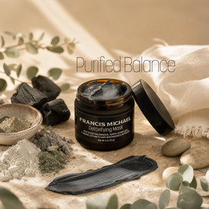A jar of Francis Michael Detoxifying Mask with its lid off, surrounded by skincare ingredients, charcoal, eucalyptus leaves, and a white cloth on a neutral beige background. The text 'Purified Balance' is overlaid at the top.