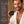A man in a white robe holds a black jar of the Francis Michael Detoxifying Mask against a warm bathroom background, with a text panel on the left detailing the product's benefits.